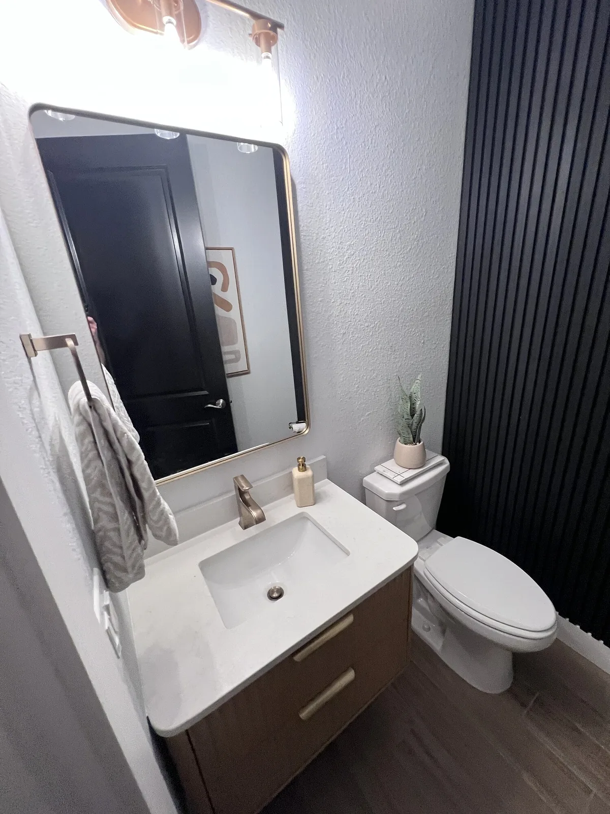Modern half bath with a floating vanity and black fluted feature wall in Ponte Vedra, Florida