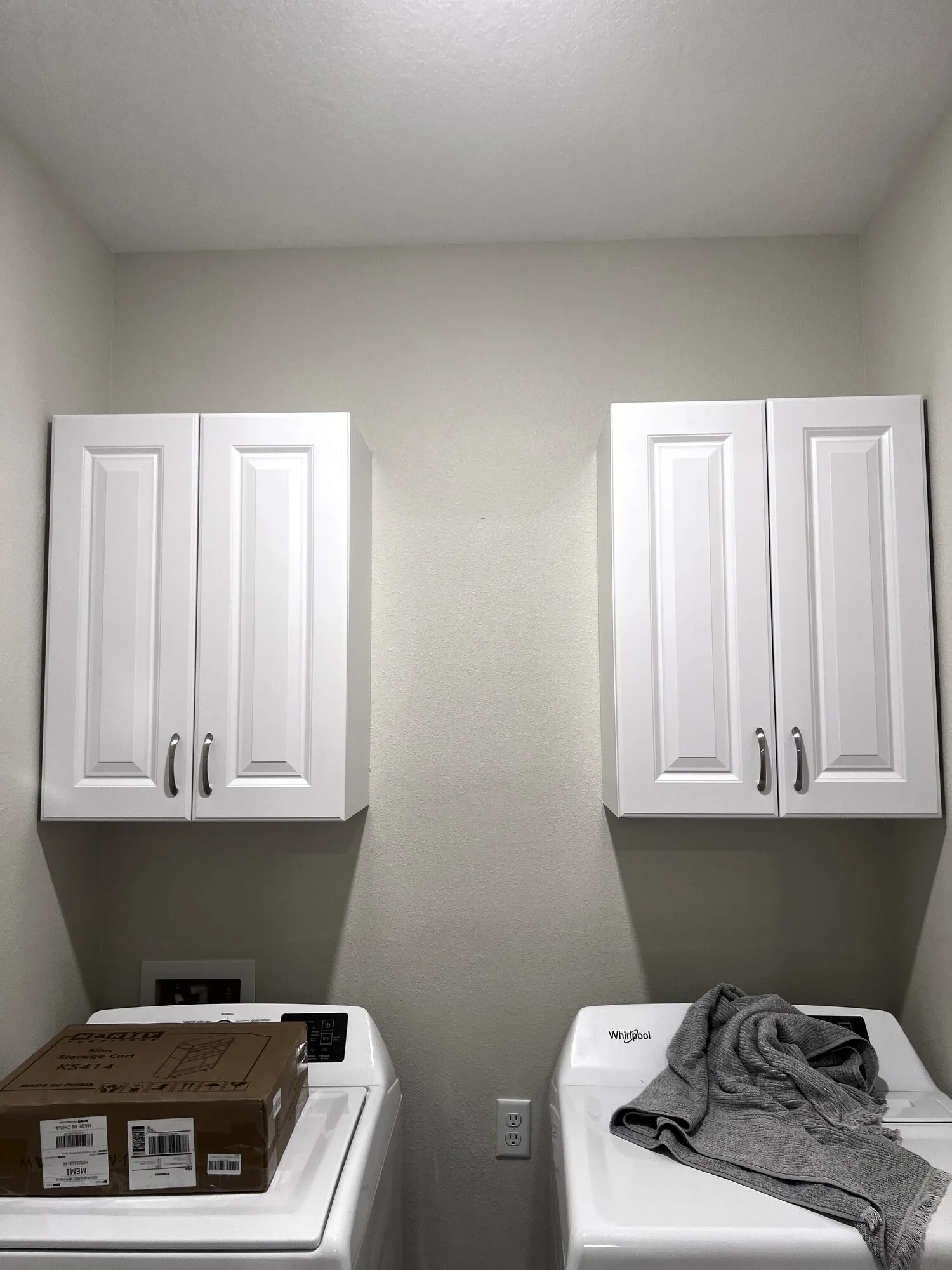 Finished white wall cabinets above a Yulee laundry area
