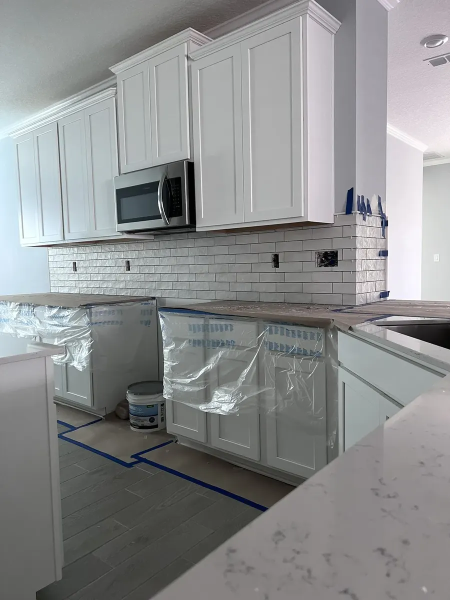 Ceramic tile installation progressing around the kitchen cabinets