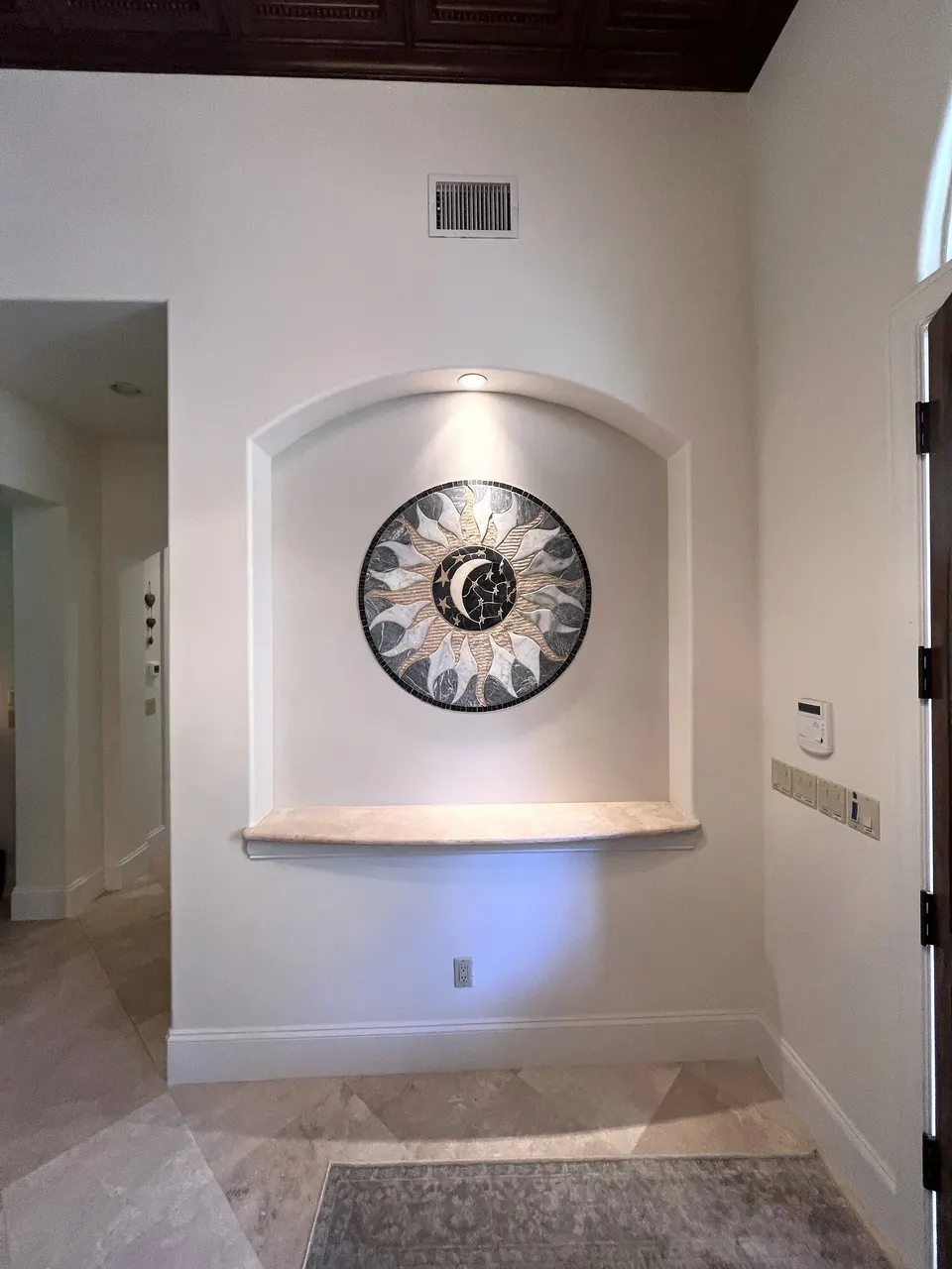Finished sun mosaic centered in an entryway niche