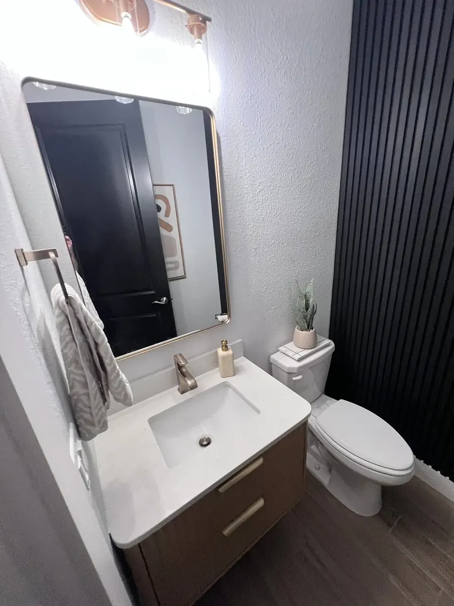 Modern half bath with a floating vanity and black fluted feature wall in Ponte Vedra, Florida
