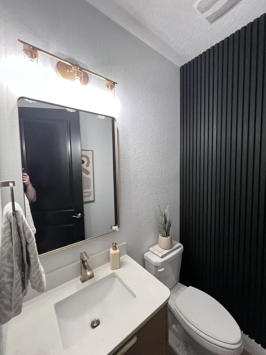 Completed half bath with floating vanity, mirror, and fluted wall