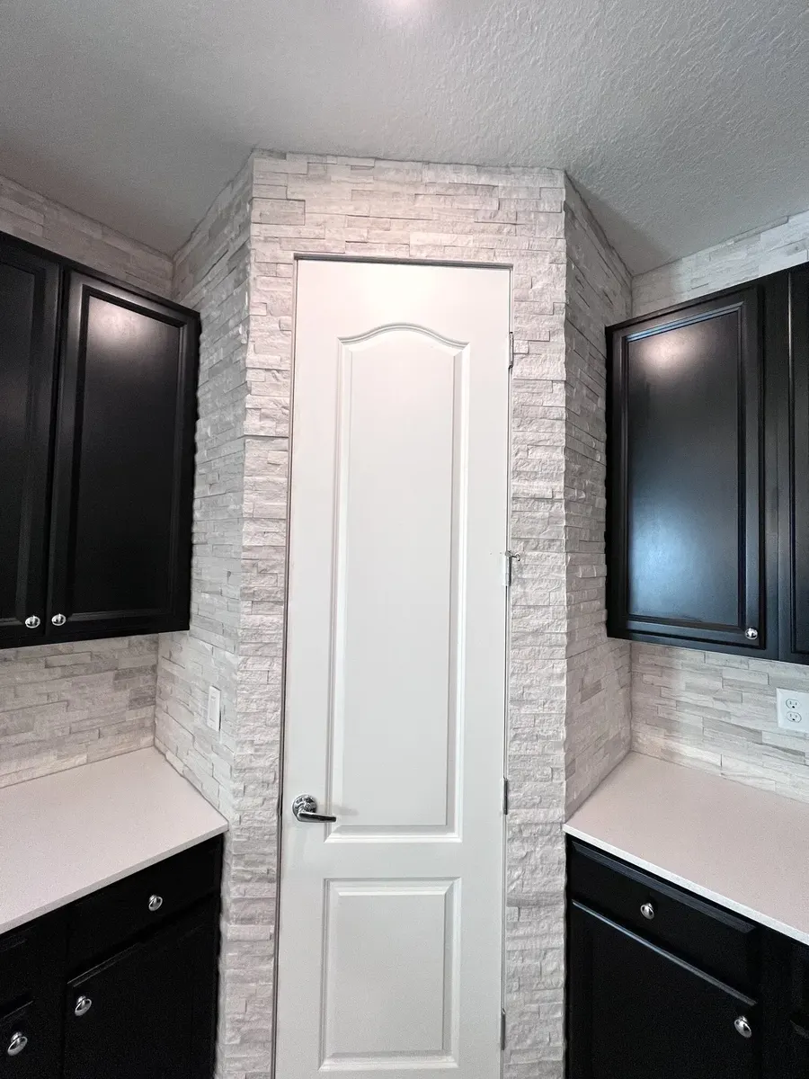 Finished split-face marble wrapping the kitchen doorway and cabinets
